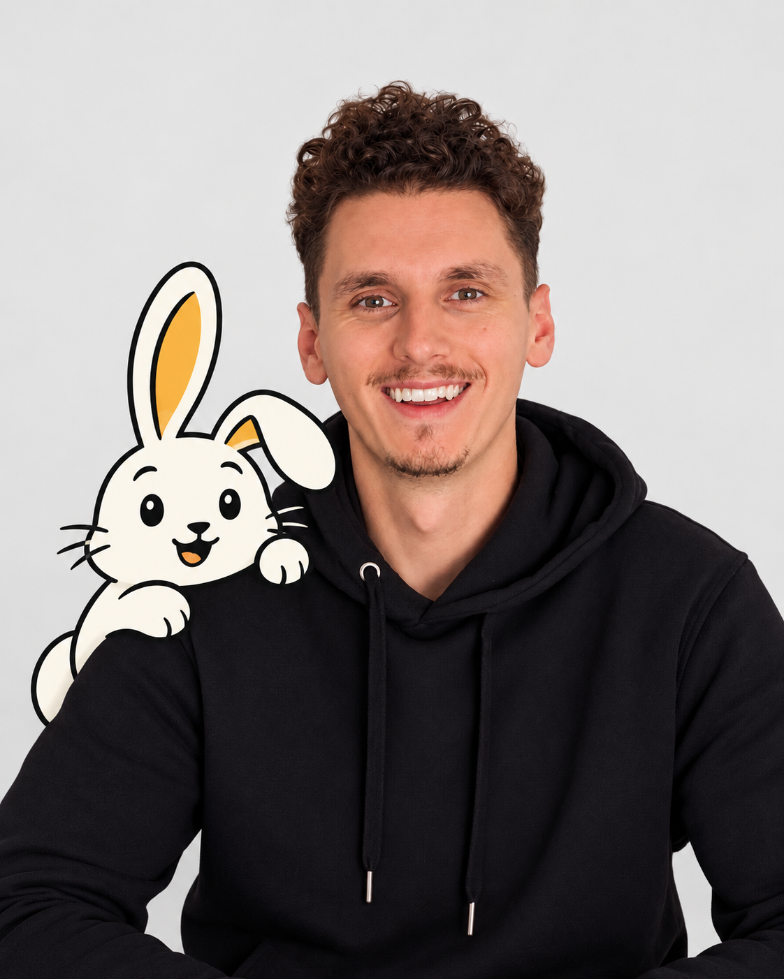 Dan smiling in a black hoodie with Mintmere Bunny peeking over his shoulder